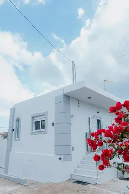 a white building with red flowers in front of it at AITHRA seaside in Arónion