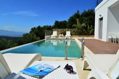 a swimming pool with a table and chairs next to a house at Villa Marie Homeleader in Delimanolianá