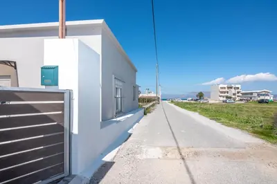 a white building with a gate on the side of a road at Margie's Apartments in Kissamos