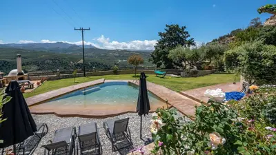 a swimming pool in a garden with chairs and umbrellas at Villa Dimmare by PosarelliVillas in Kissamos