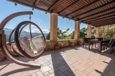 a hanging chair on a patio with a table at Villa Dimmare by PosarelliVillas in Kissamos