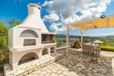an outdoor oven with a table and chairs on a patio at Villa Faye by PosarelliVillas in Metókhion
