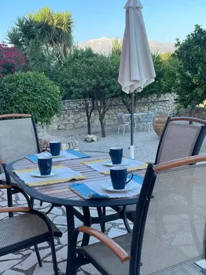 a table with cups and an umbrella on a patio at Dans une villa avec piscine privée, calme, proche des plages, vues mer et montagnes in Tsivarás