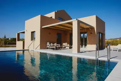 a villa with a swimming pool in front of a house at Giannoulis Ele Villas in Skoutelónas