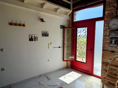 a red door in a room with a clock on the wall at Restored traditional stone House-Magazi in Sirílion