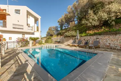 a swimming pool with chairs and a house at Dimosthenis by Vintage Travel in Stalos