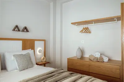 a bedroom with a bed with a wooden dresser and a window at Ethereal White Villas in Gramvousá