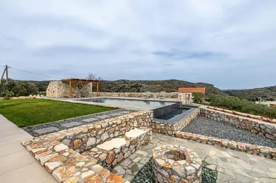 a backyard with a swimming pool and a stone wall at Villa Alargo Heated Pool in Katokhórion