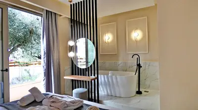 a bathroom with a tub and a large mirror at GoldenRoyalSuites in Stalos