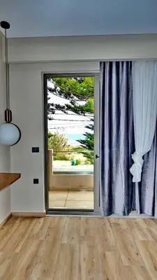 a room with a sliding glass door with a view of the ocean at GoldenRoyalSuites in Stalos
