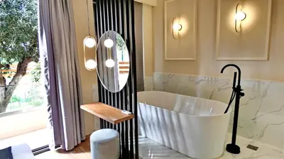 a bathroom with a tub and a large mirror at GoldenRoyalSuites in Stalos