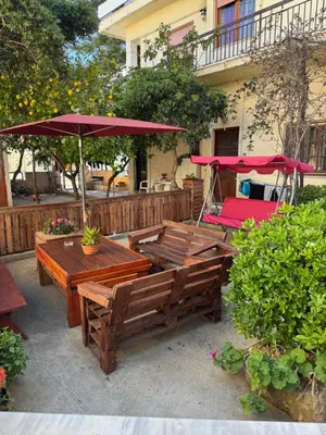 a patio with wooden tables and a red umbrella at Mike's appartments in Chania Town