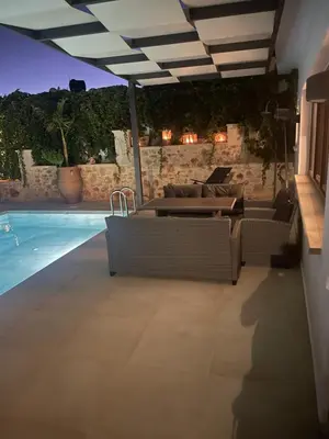 a patio with tables and chairs and a swimming pool at Villa Cisternis in Stérnai