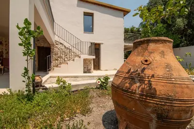an old rusty vase in front of a house at Το Ρόδι Voutas Cottage house in Palaiochóra