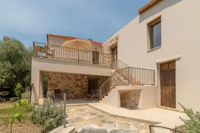 a large white house with a balcony and stairs at Το Ρόδι Voutas Cottage house in Palaiochóra