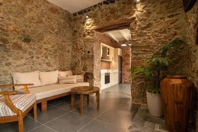 a living room with a couch in a stone wall at Το Ρόδι Voutas Cottage house in Palaiochóra