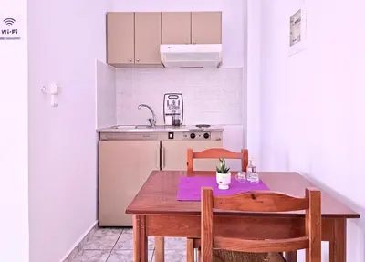 a kitchen with a wooden table with two chairs and a sink at Inna Rooms in Fournádhos