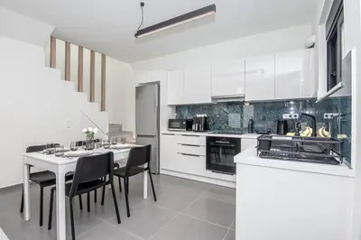 a kitchen with white cabinets and a table and chairs at Tolis Exclusive Villa in Kissamos