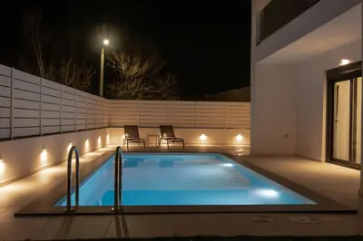 a swimming pool with lights on a house at night at Tolis Exclusive Villa in Kissamos
