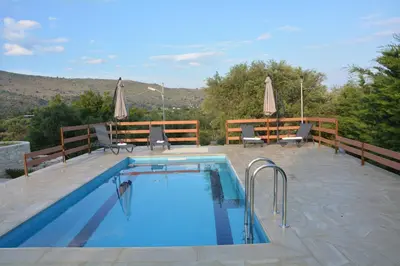 a swimming pool on a patio with chairs and umbrellas at Villa Ikaros in Kalamitsi Amygdali