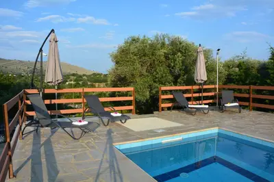 a pool with chairs and umbrellas on a patio at Villa Ikaros in Kalamitsi Amygdali