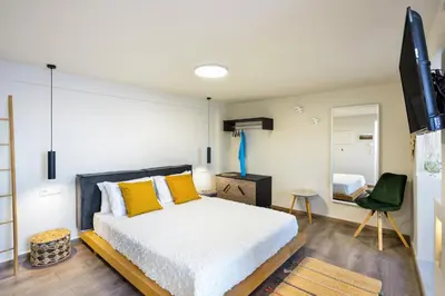 a bedroom with a bed with yellow pillows and a television at Kumka seafront suite in Chania Town