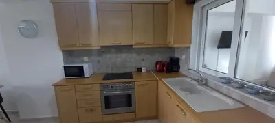 a kitchen with wooden cabinets and a sink and a microwave at Seaside apartment in Chania in Chania Town