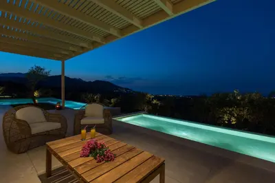 a patio with a table and chairs and a swimming pool at Villa Ianira in Kolymvari