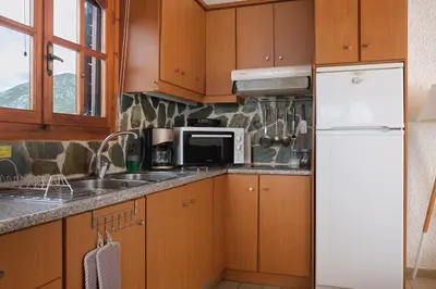 a kitchen with wooden cabinets and a white refrigerator at Batilas House next to exotic beach of Elafonisi in Elafonisi