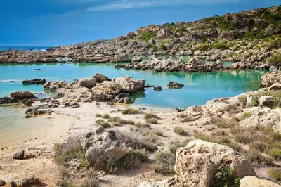 a beach with rocks and blue water at Batilas House next to exotic beach of Elafonisi in Elafonisi