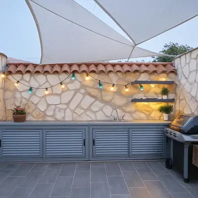 an outdoor kitchen with a stone wall and an umbrella at Serena Residence in Chania Town