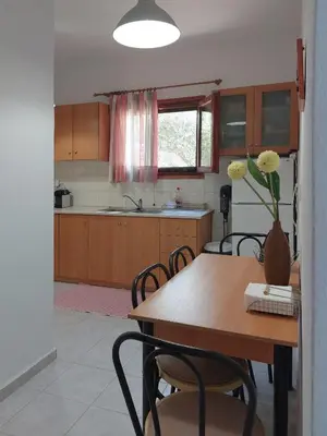 a kitchen with a wooden table and chairs and a table with flowers at Stavros Oak Tree House in Vasilópoulon