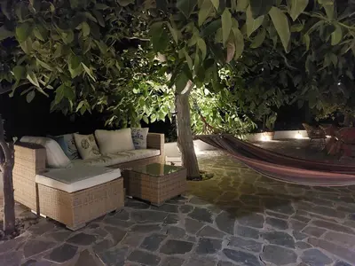 a hammock and a couch on a patio with a tree at Stavros Oak Tree House in Vasilópoulon