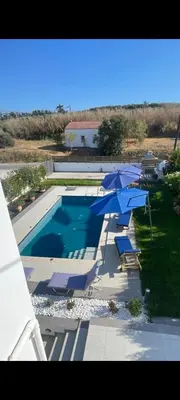 a swimming pool with umbrellas and chairs and a swimming pool at Villa Anastasia Sissy in Módhion