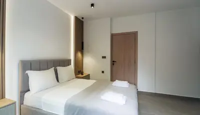 a bedroom with a white bed and a wooden door at Seascape Luxury Apartment 2 in Kounoupidhianá