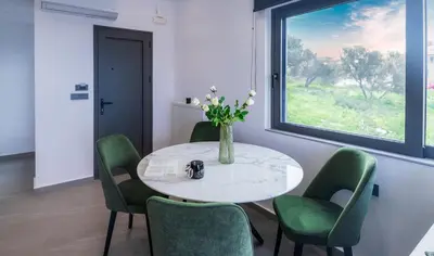 a dining room with a table and green chairs at Seascape Luxury Apartment 2 in Kounoupidhianá