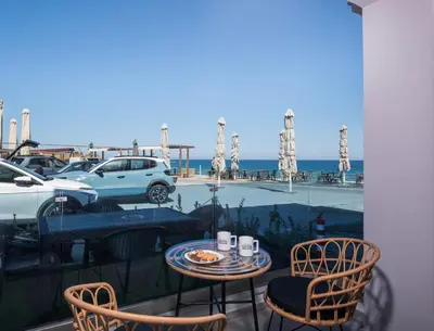 a table and chairs on a balcony with a view of the ocean at Blue Balcony - Boutique Beachfront Suite with Private Parking Spot in Chania Town