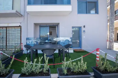 a patio with a table and chairs in front of a building at Blue Balcony - Boutique Beachfront Suite with Private Parking Spot in Chania Town