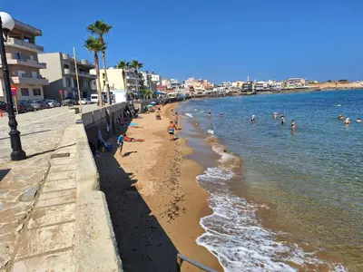 a beach with a group of people in the water at Blue Balcony - Boutique Beachfront Suite with Private Parking Spot in Chania Town