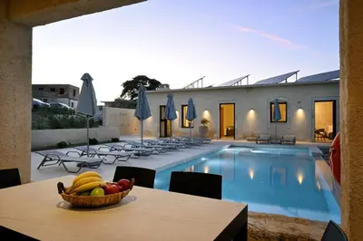 a bowl of fruit on a table next to a swimming pool at Evans Villas in Kissamos