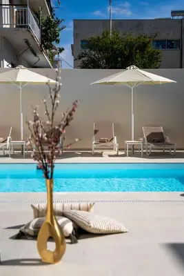 a vase with flowers in it next to a swimming pool at Selected Suites in Chania Town