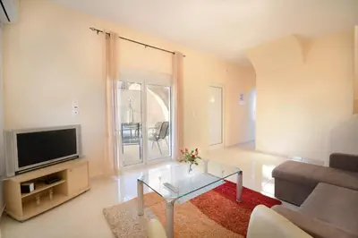 a living room with a glass coffee table and a television at Villa Silvia by Andrian Villas in Kalamítsion Alexándrou