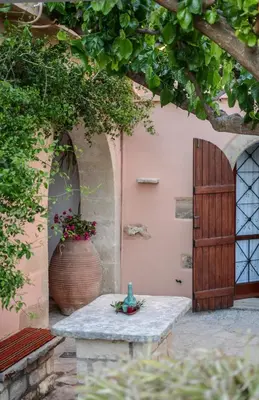a patio with a table and a wooden door at Villa Rouga by Andrian Villas in Kalamítsion Alexándrou