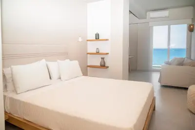 a bedroom with a white bed with a view of the ocean at Elia Suites in Falasarna
