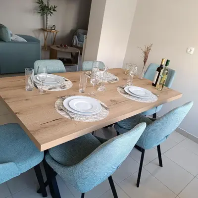 a wooden table with chairs and plates and wine glasses at Del's Apartment in Chania Town