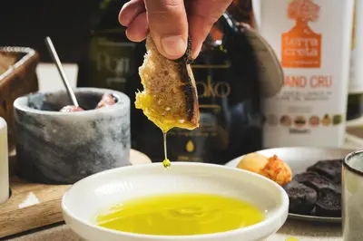 a person dipping a piece of food into a bowl of soup at Elysia Boutique Hotel in Chania Town