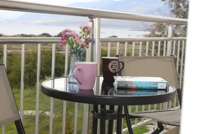 a table with books and a cup and flowers on a porch at Sea Sight Vibes in Frangokastello