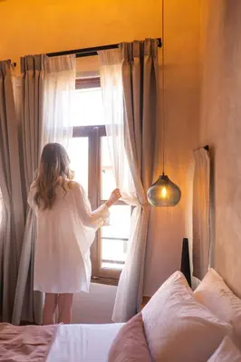 a little girl in a white dress looking out of a window at Mimosa Veneziano - Sauna - Old Town Chania in Chania Town