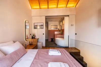 a bedroom with a bed and a bathroom with a tub at Mimosa Veneziano - Sauna - Old Town Chania in Chania Town