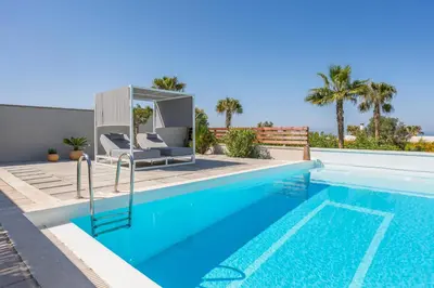 a swimming pool with two chairs next to a house at Natura Hill Villa II Sunset View in Kounoupidhianá